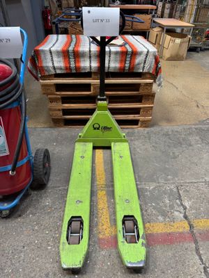 un chariot élévateur vert posé à côté d'un extincteur rouge