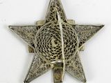 an antique silver star broochle with intricate design on a white background
