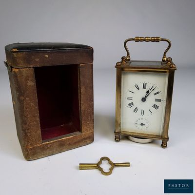 une petite horloge posée à côté d'une boîte contenant une clé