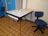 a desk with a chair and a blue cabinet in the background