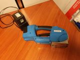 une agrafeuse bleue posée sur une table en bois, à côté d'un téléphone portable