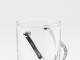 un verre contenant une cuillère, posé sur une surface blanche