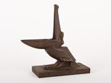 une statue en bronze représentant un pélican perché sur un socle en bois