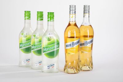 quatre bouteilles d'alcool sont alignées sur une surface blanche
