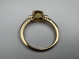 a close up of a gold ring with a green stone