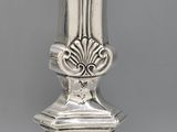 an antique silver vase sitting on top of a table next to a white wall