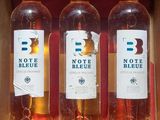 three bottles of wine in a cardboard box on a shelf