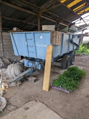 un camion-benne bleu garé à côté d'un tas d'ordures
