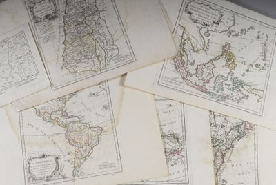 Plusieurs anciennes cartes du monde sont posées sur une table