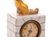 une figurine représentant un homme assis sur le cadran d'une horloge