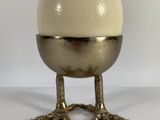 an egg sitting on top of a metal stand on a white surface
