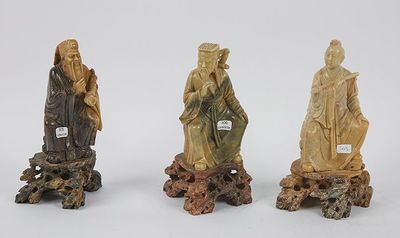 trois figurines chinoises sculptées représentant un homme et une femme, posées sur une souche d'arbre