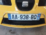 the front of a yellow car with a license plate on it ' s bumper