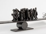 une sculpture représentant un groupe de personnes sur une balançoire à bascule