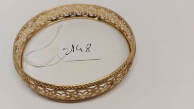 un gros plan d'un bracelet en or posé sur une surface blanche