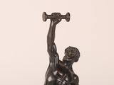 bronze statue of a man lifting a barbell on a marble base