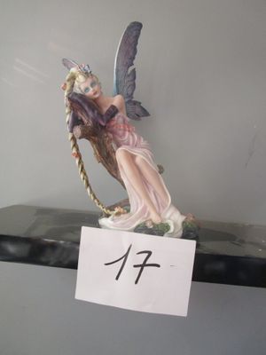 une figurine représentant une fée assise sur une étagère