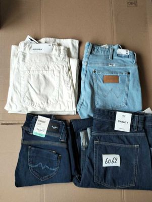 three pairs of men ' s jeans are sitting on a cardboard box