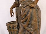 bronze statue of a woman with a basket on a black surface