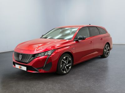 Une voiture rouge est garée dans une pièce au sol noir.