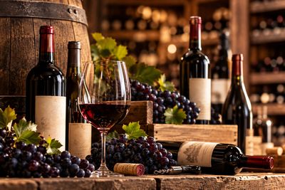 bottles of wine and glasses of wine sit on a table in front of a barrel