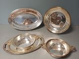 trois plats en métal argenté posés sur une table, avec un miroir au milieu
