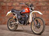 a red and white dirt bike parked in front of a brick wall