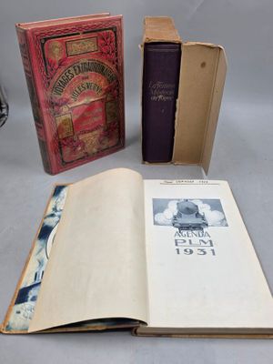 Plusieurs livres sont posés sur une table, avec une horloge en arrière-plan.