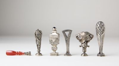 five silver vases and a red toothbrush on a white surface
