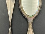 a silver mirror and a silver spoon on a table
