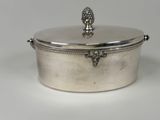 an antique silver plated casserole with a lid on a white surface