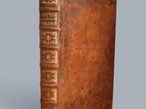 un vieux livre avec une couverture en cuir marron sur fond gris