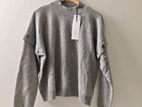 Le pull est suspendu à un cintre accroché au mur.