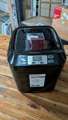 une petite machine à laver noire posée sur une table en bois