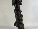 a black sculpture of a woman with a head on a wooden base