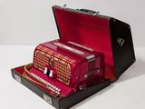 a red accordion sitting in a case on a white surface