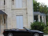 a black convertible car parked in front of a large house