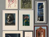 many framed pictures hanging on the wall above a bed