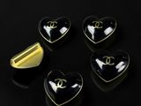 four heart shaped black and gold brooches on a black surface