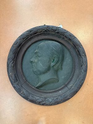 a bronze portrait of a man in a round frame