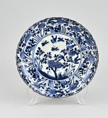 assiette bleue et blanche ornée de fleurs et d'oiseaux, posée sur un socle