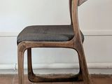 a wooden chair with a black seat on a brick floor