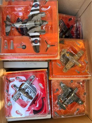 des boîtes contenant des jouets variés, rangées dans un carton posé sur une table