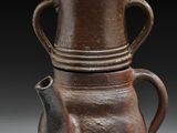 une paire de vases marron avec couvercles et anses, posés sur un fond gris
