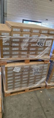 un homme debout à côté d'une pile de cartons dans un entrepôt