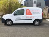 the white van is parked in front of a building with a red and white sign on it