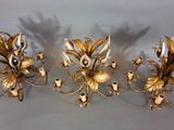 two gold colored sconces with flowers and candles on a table