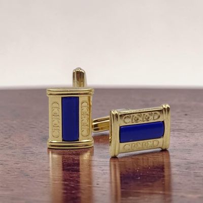 une paire de boutons de manchette dorés et bleus posés sur une table en bois
