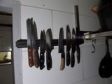 many knives hanging on the wall in the kitchen
