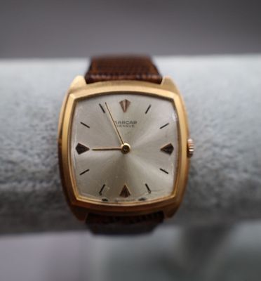 un gros plan d'une montre en or posée sur un tissu blanc